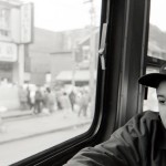 Adolescent boy sitting in street car with baseball hat that says Six Nations