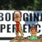 Toy figurines of Indian couple in traditional attire foreground, sign saying Aboriginal Experiences in background, outside