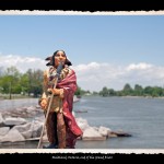 Toy figurine of Indian man in traditional dress and wrapped in red robe in foreground, sunny wide river scene in background