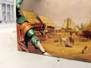 detail shot of construction boards with replication of a painting with scene of Indian village, behind the boards the classical architecture of the Royal Ontario Museum