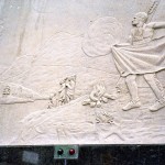 Stone carving frieze with scene of Indian man in traditional dress and campfire in front of him